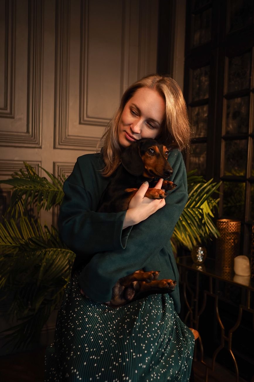 A woman lovingly holding her dachshund indoors, showcasing warmth and companionship.